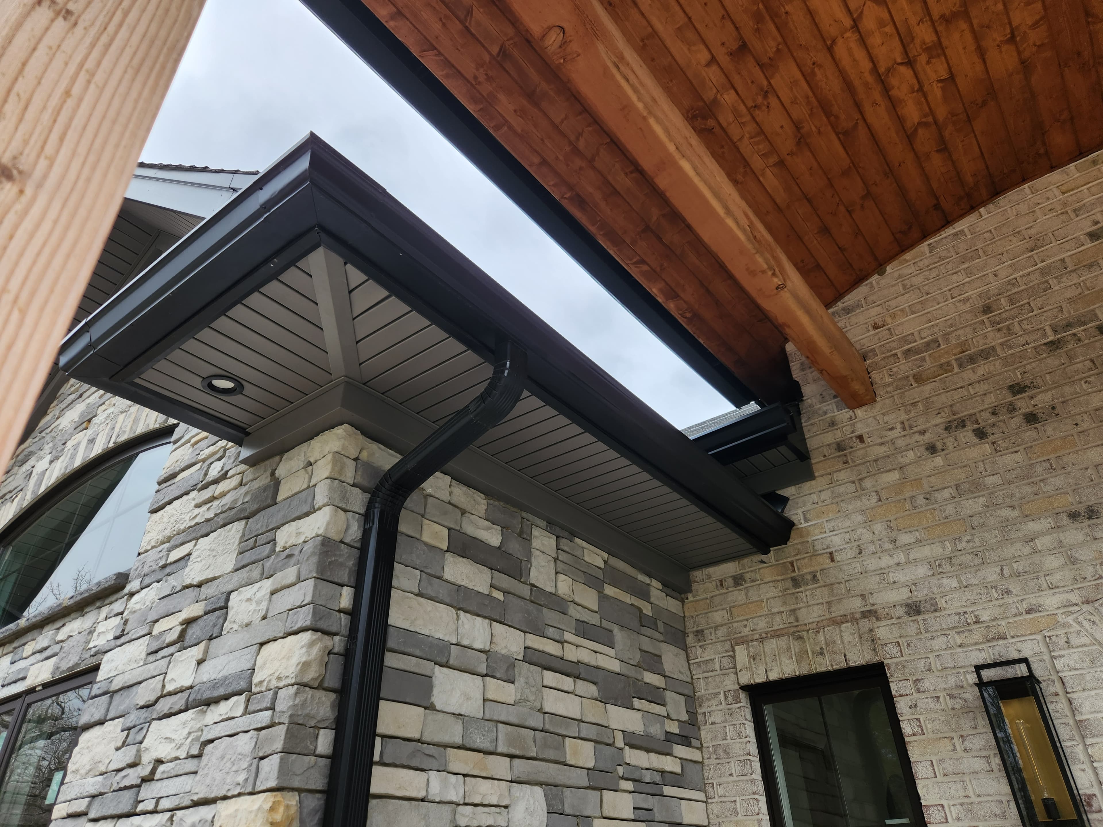 Dark gutters on custom stone home — high-end install