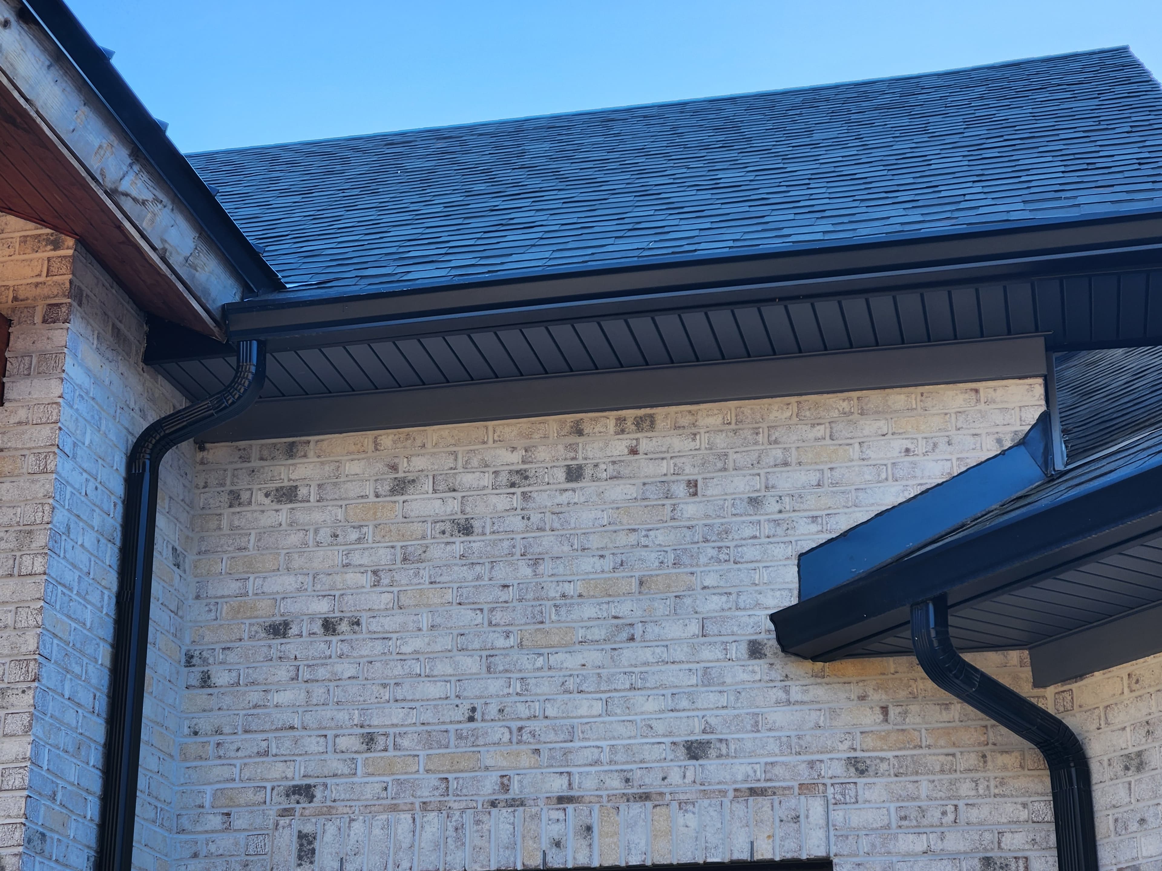 Black seamless gutters and downspout — close-up detail