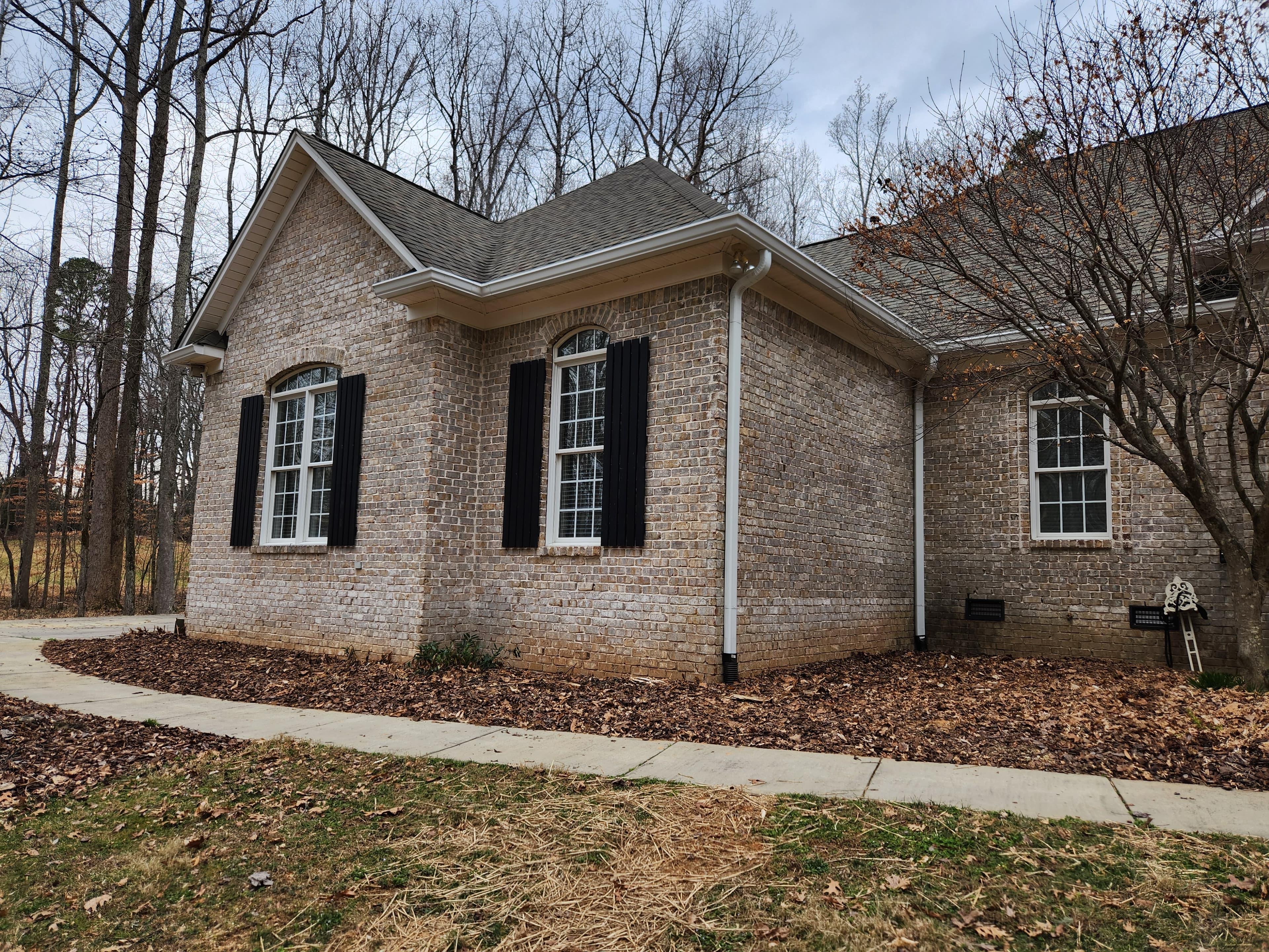 Brick home with arched windows and white seamless downspout in NC