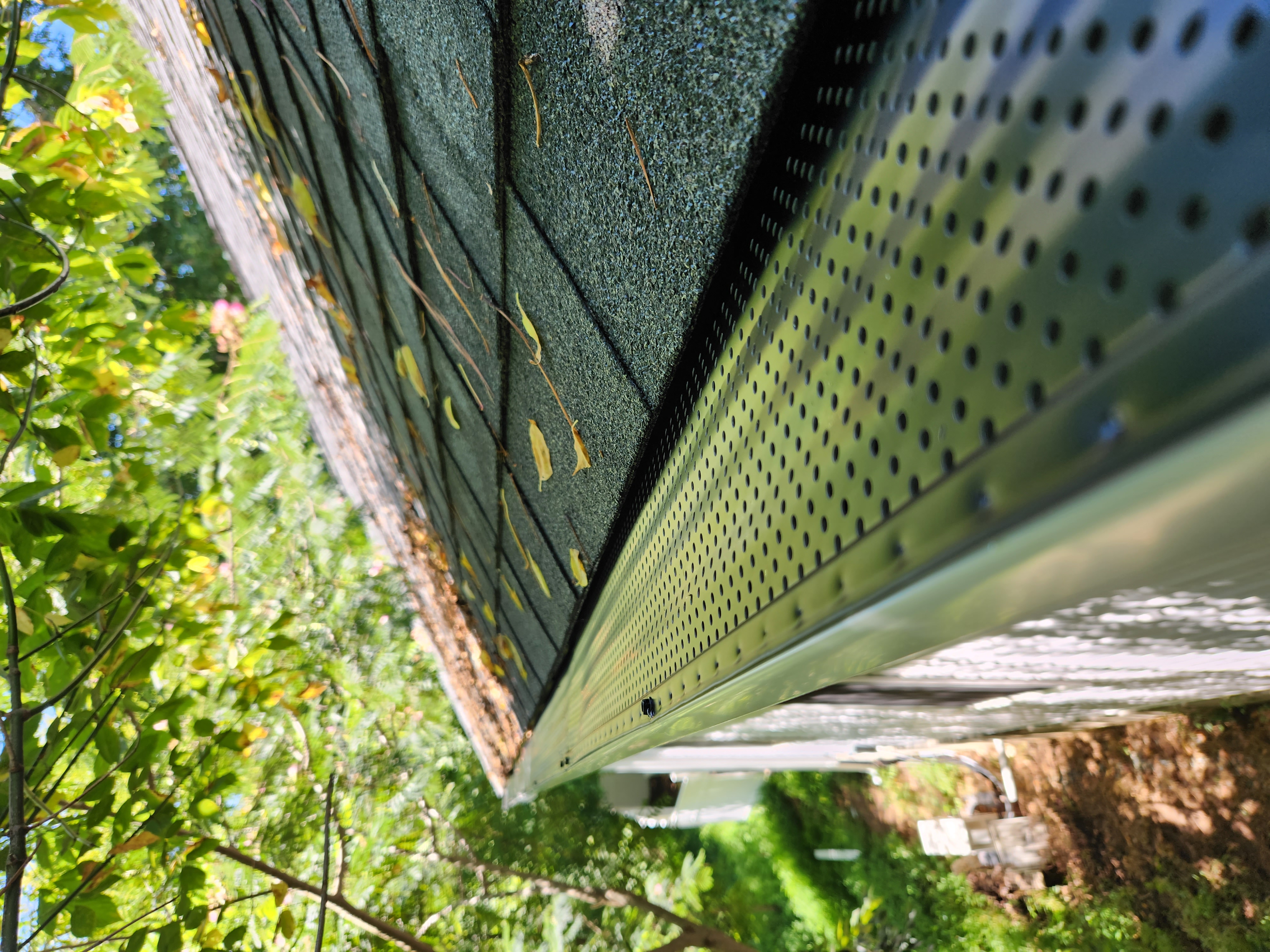 Perforated aluminum gutter guard installed on shingle roof