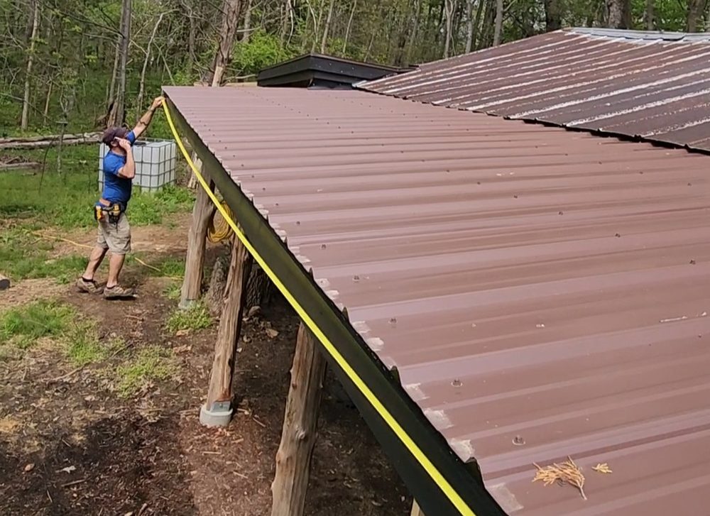 Freedom Gutters measuring a metal roofline for proper gutter sizing, Alamance County NC